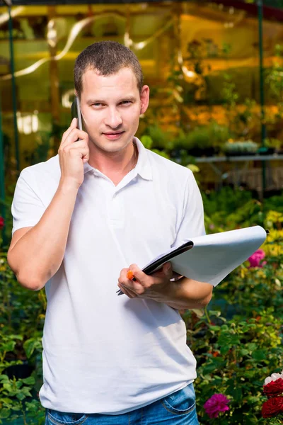 Retrato de un hombre de negocios con un teléfono en un invernadero — Foto de Stock
