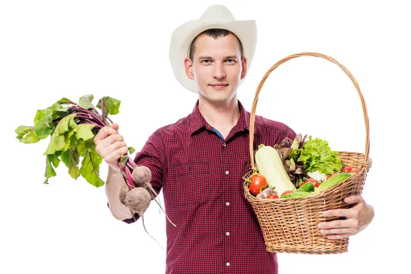 Jonge man met een mandje met groenten uit de tuin op een wit — Stockfoto
