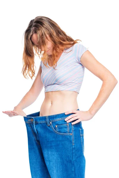 Donna che sbircia in jeans di grandi dimensioni su sfondo bianco — Foto Stock