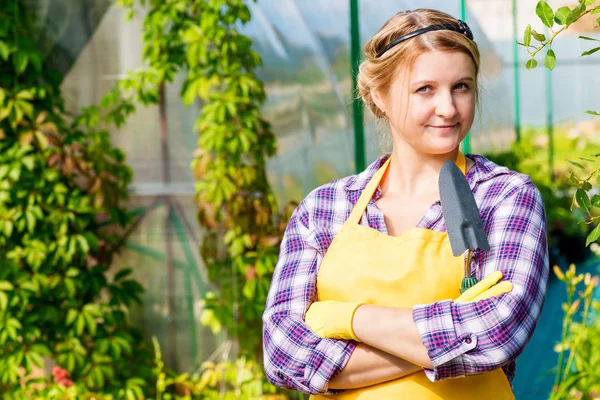 Beautiful young girl working in a greenhouse gardener — Stock Photo, Image