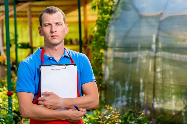 Man gardener with a blank for recording on a background of plant — Stock Photo, Image