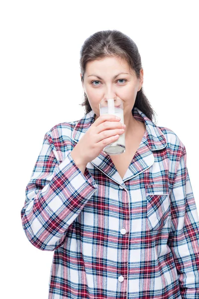 Frau im karierten Pyjama trinkt vor dem Schlafengehen Milch auf weißem Rücken — Stockfoto