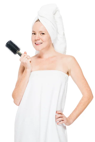 Woman with comb in hand is dressed in towel after shower on whit — Stock Photo, Image