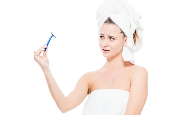 Girl looks at the razor with neglect on a white background — Stock Photo, Image