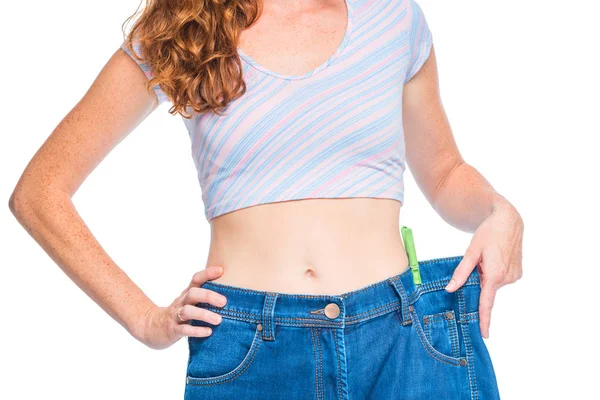 Slim flicka förlorade vikt, försöker på gamla jeans på vit bakgrund — Stockfoto