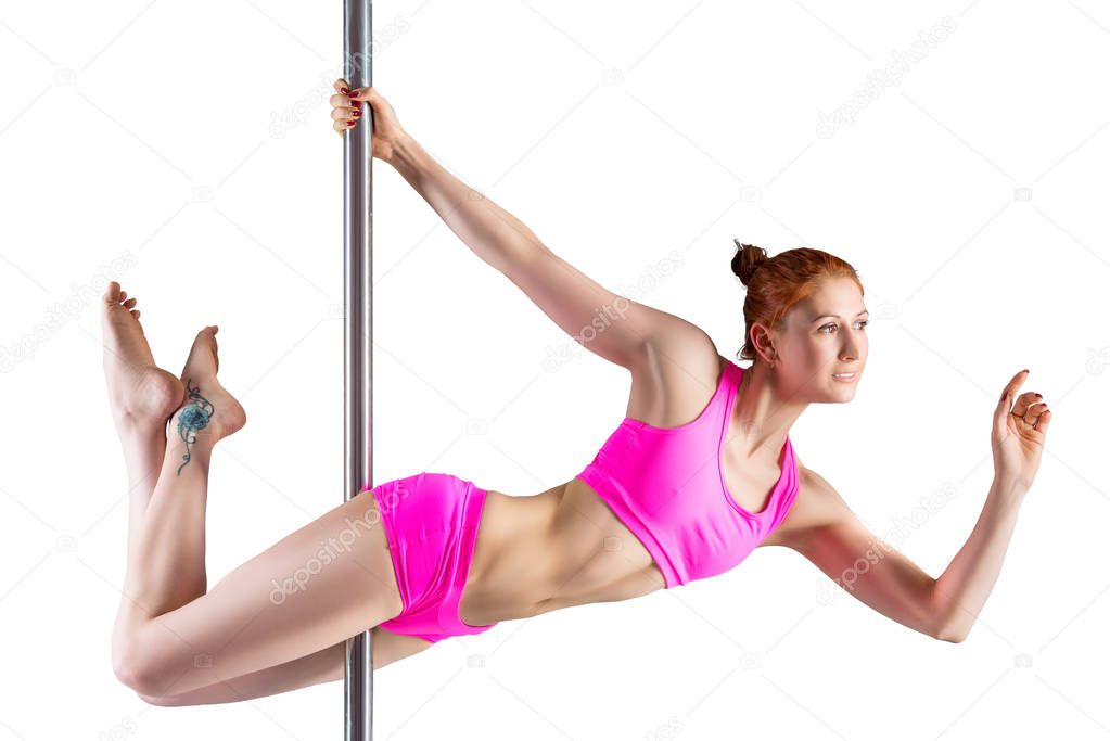 Female athlete in a pink suit on a pylon performs an exercise, i