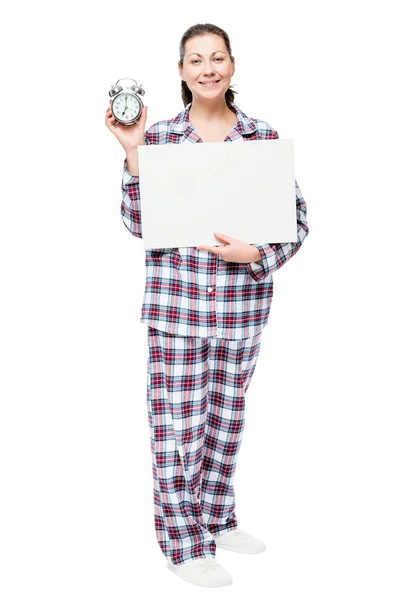Brunetka dziewczyna w piżamie gospodarstwa plakat i Wyświetlono cloc alarmu — Zdjęcie stockowe