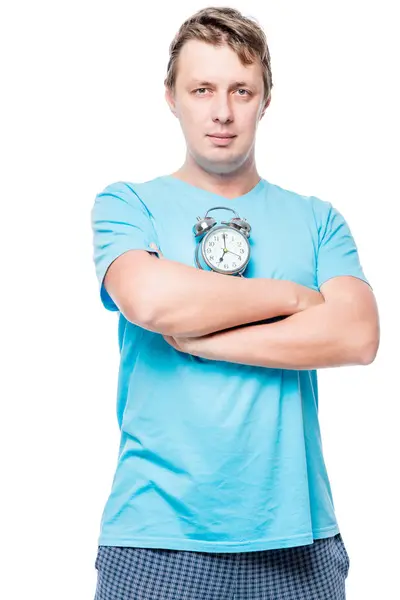 Vertical portrait of a man in pajamas with an alarm clock on whi — Stock Photo, Image