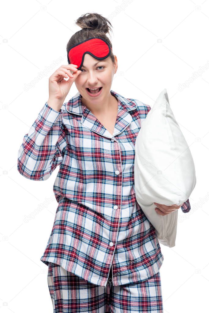 Beautiful cheerful woman in pajamas and a mask for sleep holds a