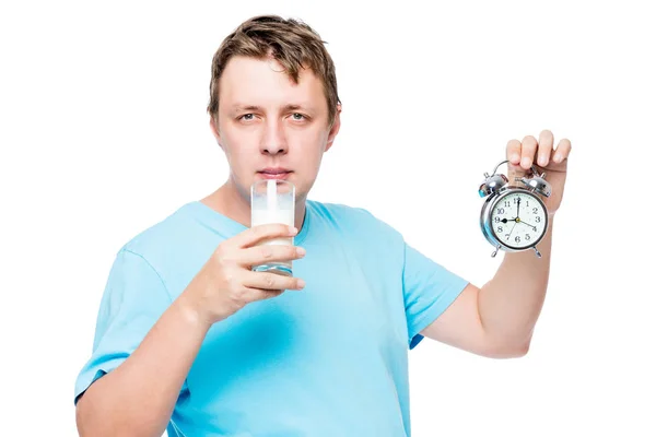 Porträtt av en man med ett glas mjölk och en väckarklocka på sängen — Stockfoto