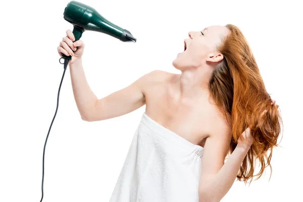 Mujer pelirroja seca el cabello con un secador de pelo en un fondo blanco — Foto de Stock