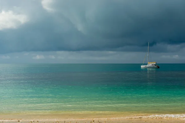 Pochmurnou oblohu nad tyrkysové moře klidné a malé bílé yach — Stock fotografie
