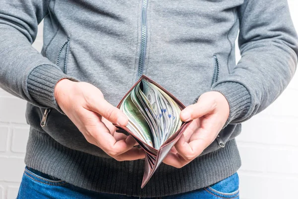Кожаная сумочка в мужских руках полна долларов — стоковое фото