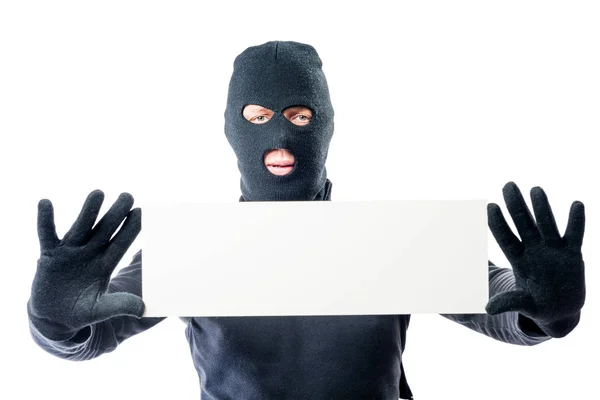 Robber in black clothes and mask with a poster in hands on a whi — Stock Photo, Image