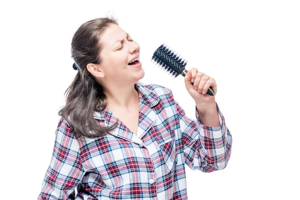 Emocionální dívka v pyžamu zpívá v kartáč na bílém poz — Stock fotografie