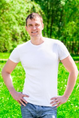 35 yaşında bir T-shirt ve jeans parkta gülümseyen adam