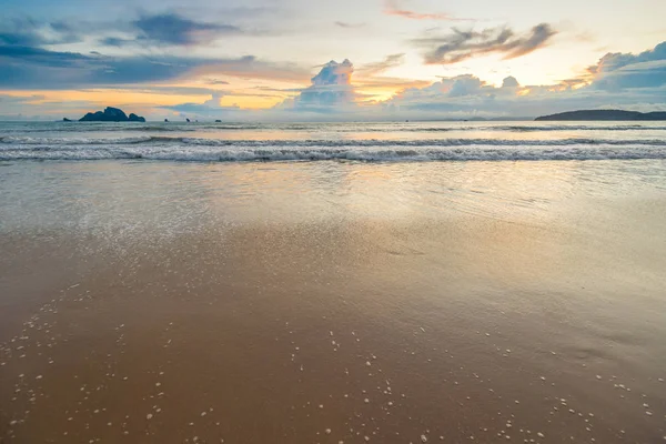 Playa de arena y olas contra el sol poniente en el horizonte —  Fotos de Stock