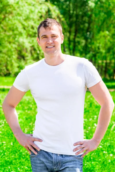 35 anni uomo sorridente in una t-shirt e jeans nel parco — Foto Stock