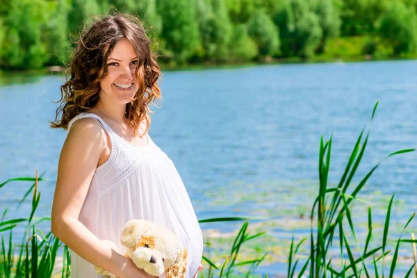 Linda chica embarazada en el fondo de un hermoso lago en el — Foto de Stock