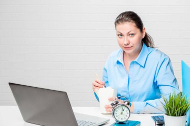 Çok yoğun çalışan dizüstü bilgisayar ile çalışma masasında erişte yiyor