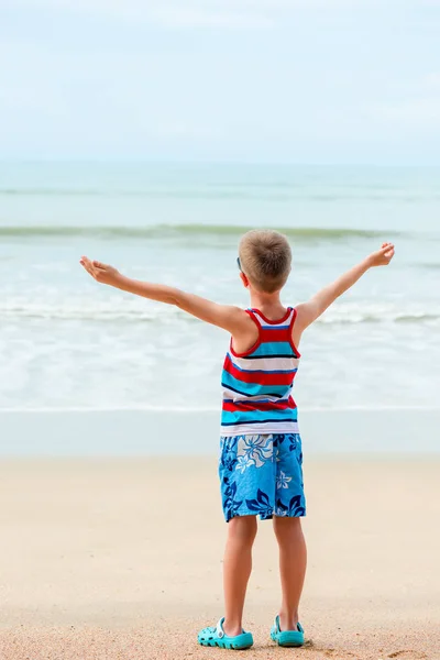 The boy with arms stretched out to the sides rests by the sea — Stock Photo, Image