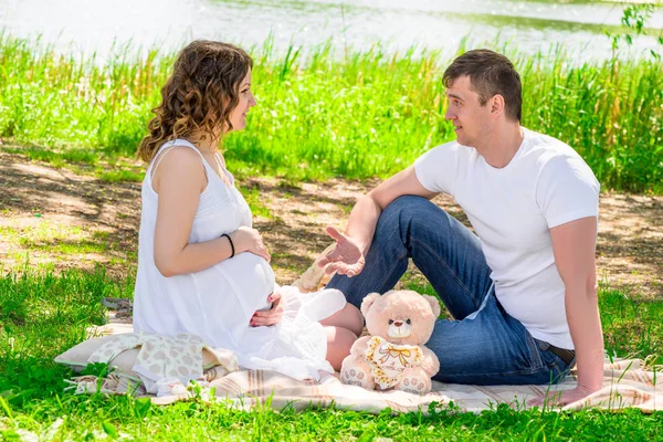 Mann und seine schwangere Frau ruhen sich auf einem Picknick in einem Park in der Nähe der — Stockfoto