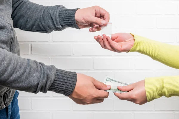 Man sells a woman a dose of drugs against a brick wall backgroun — Stock Photo, Image