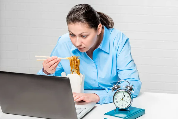 Ocupada mujer de negocios con fideos trabajando en el ordenador portátil en la oficina —  Fotos de Stock