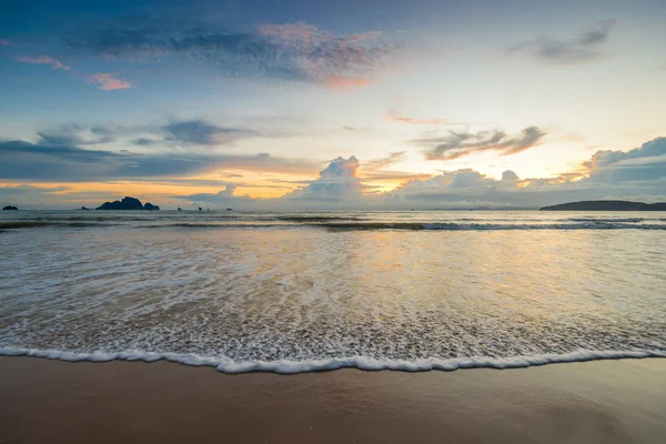 Köpüklü deniz dalga kumlu bir plaj üzerinde gün - gün batımı zamanı