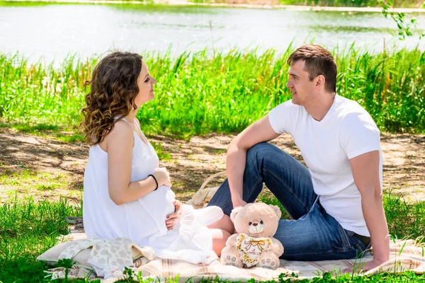 Feliz pareja amorosa en anticipación de un niño descansando en la naturaleza — Foto de Stock