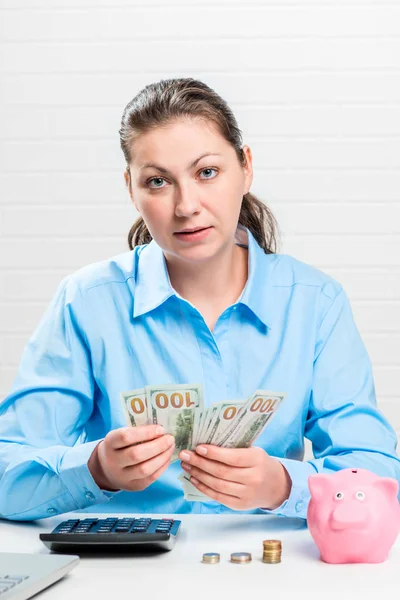 Businesswoman businesswoman counts dollars, near her a pink pigg — Stock Photo, Image