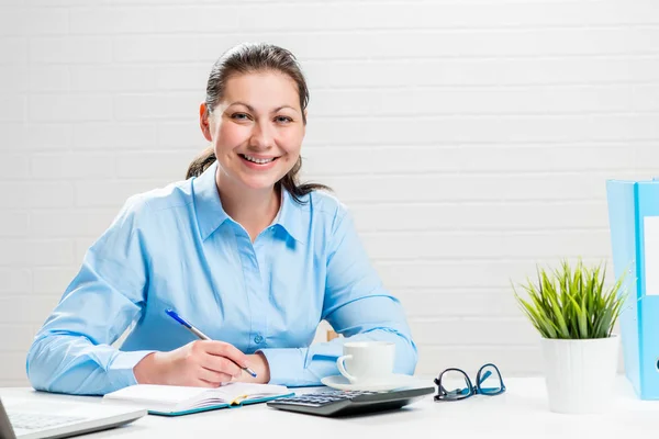 Portrait of a businesswoman at a white table in an office at wor — Stock Photo, Image