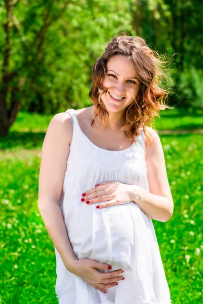 Vrouw houden haar handen buik, te wachten voor het kind op het park — Stockfoto