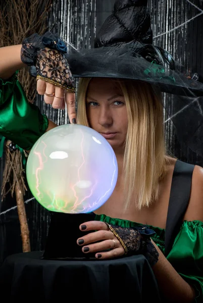Belle sorcière sur fond noir avec une boule magique — Photo