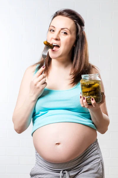 Hungriga gravid kvinna med en burk inlagda gurkor mot en — Stockfoto