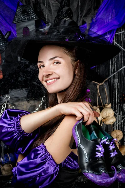 Portrait d'une sorcière heureuse en costume avec des chaussures sur un backgr noir — Photo