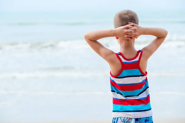 Menino relaxado em uma camiseta olha para o mar — Fotografia de Stock