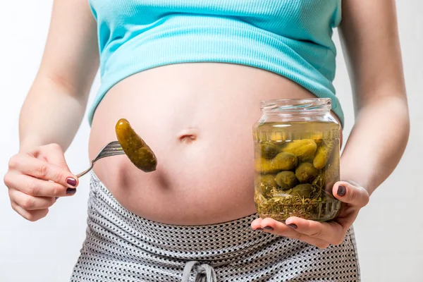 Gesalzene Gurken in einem Glas auf dem Hintergrund eines großen Bauches von — Stockfoto