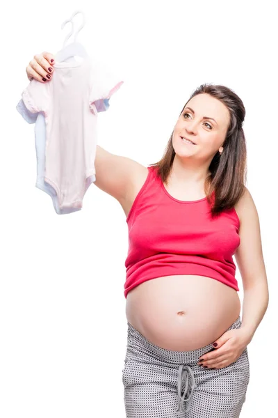 Jeune heureuse future mère choisit des vêtements pour l'enfant sur un blanc — Photo