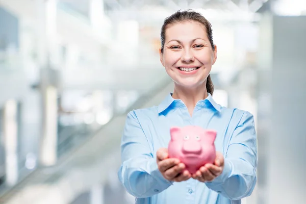 Mutlu bir kadın para, office fotoğrafta tam bir kumbara tutar — Stok fotoğraf