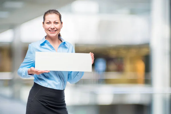 Mujer sonriente con un cartel en una camisa azul en la oficina —  Fotos de Stock