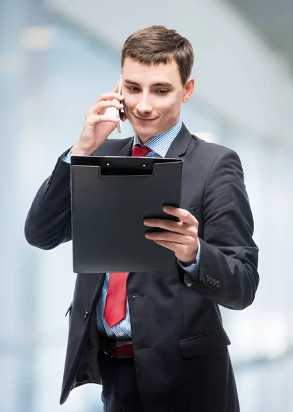 Empresário olhando em uma pasta e falando ao telefone no — Fotografia de Stock