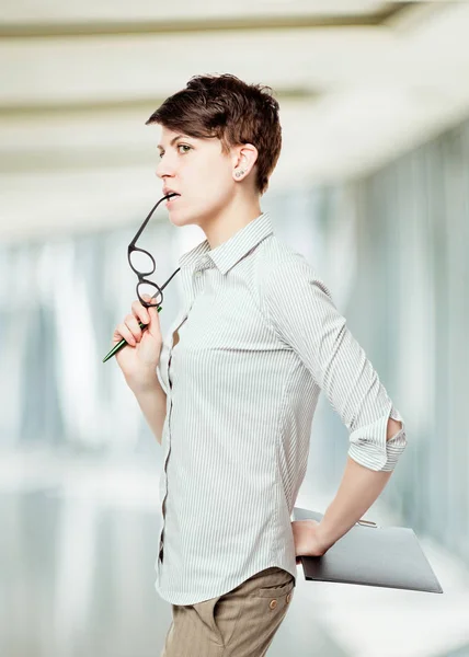 Doordachte brunette met bril in een gestreept shirt in het kantoor — Stockfoto