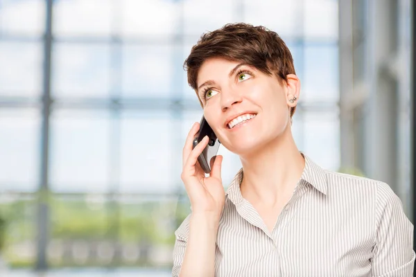 Mujer sonriente hablando en un teléfono móvil en la oficina — Foto de Stock
