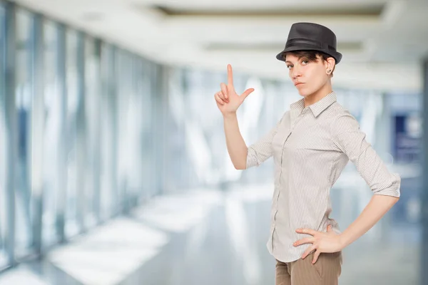 Žena v černém klobouku drží prsty zbraň v kanceláři — Stock fotografie