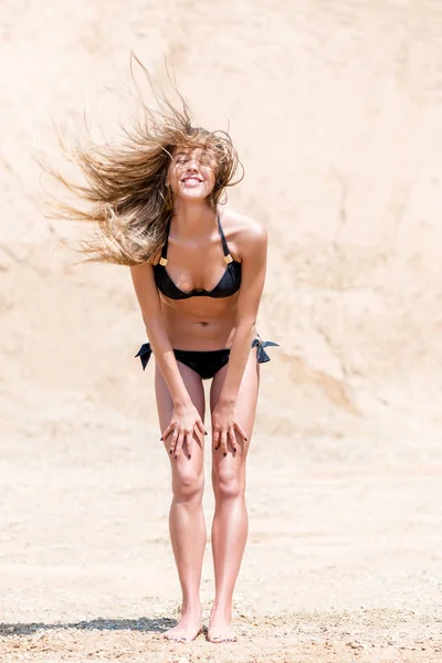 Actieve en mooie vrouw op een zand steengroeve in een bikini poseren — Stockfoto