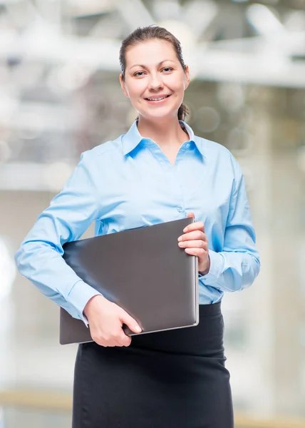 Mujer de negocios en una camisa azul en la oficina con un ordenador portátil —  Fotos de Stock