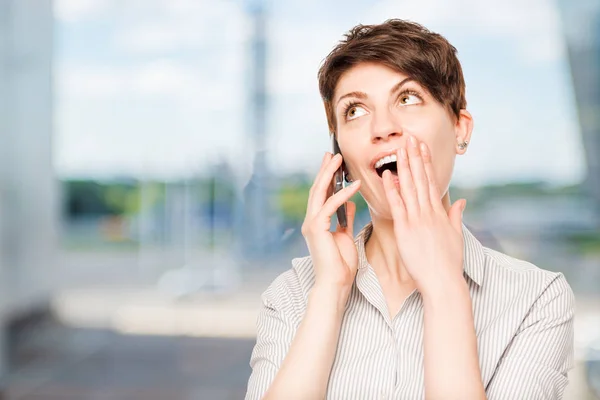 Mujer gratamente sorprendida con el teléfono móvil en la oficina — Foto de Stock