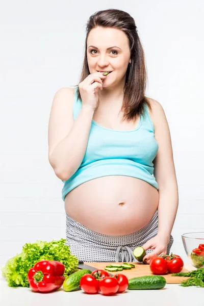 Mädchen mit dickem Schwangerschaftsbauch isst eine Gurke — Stockfoto