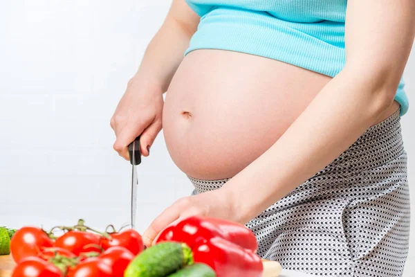 Großer Bauch der Schwangeren im Fokus, Frau bereitet Salat aus — Stockfoto
